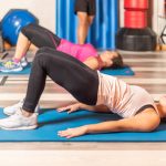 Side view of women doing pelvic exercise with trainer in gym. Concept of gym.